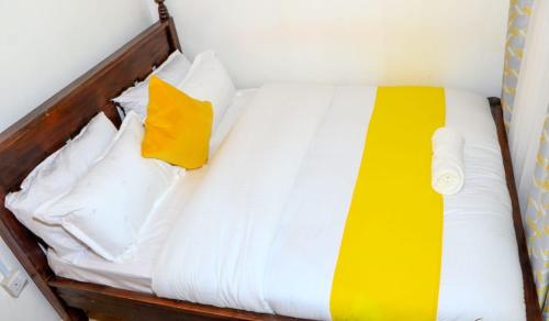 MeruPerfection的一张带白色床单和黄色枕头的床