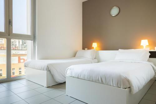 都灵圣保罗校园酒店的带窗户的客房内的2张白色床
