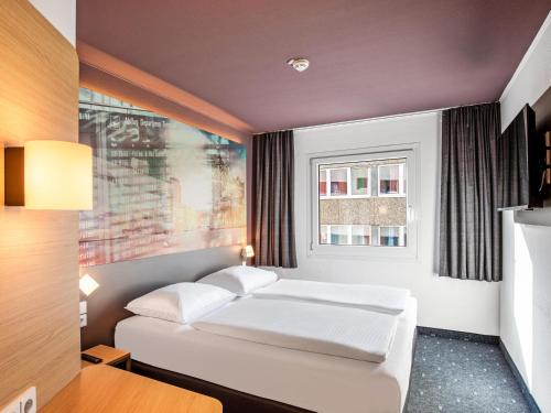 汉堡B&B Hotel Hamburg-Airport的卧室配有白色的床和窗户。