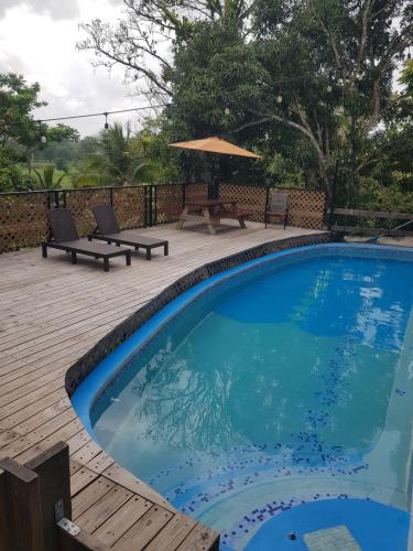 波托韦洛Rainforest Lodge del Rio的一个带野餐桌和遮阳伞的游泳池