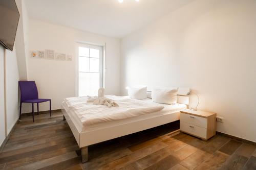 特伦特Villa Vogelblick 2的白色卧室配有一张床和紫色椅子