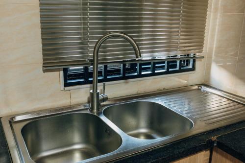 卢萨卡Epignosis Apartments的厨房里的一个不锈钢水槽,窗户