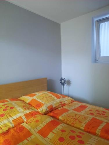 诺伊斯Apartment Am Mühlenbusch的一间卧室配有一张带黄色和橙色被子的床