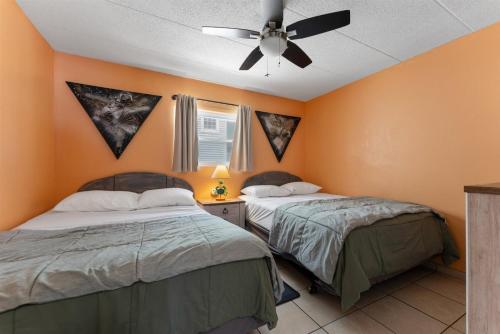 威尔伍德克拉斯特427 E Miami Ave, Unit 204的橙色墙壁客房的两张床