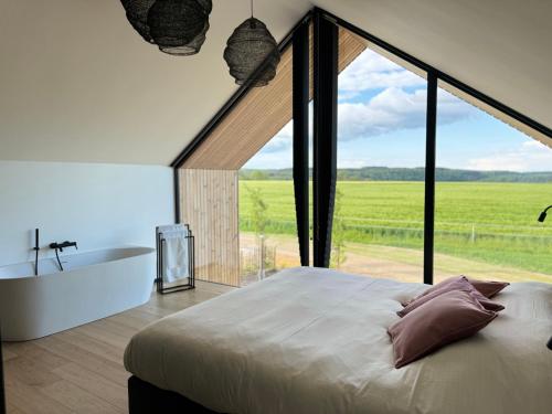 杜柏Durbuy Insolite - Natural Escape的卧室设有一张大床、一个浴缸和一个大窗户。