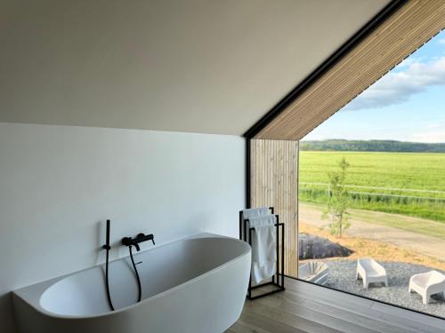 杜柏Durbuy Insolite - Natural Escape的一间带白色浴缸和大窗户的浴室