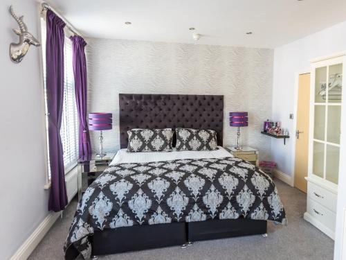布莱克浦The Kenley Hotel的一间卧室配有一张大床和紫色窗帘