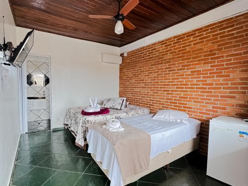 卡纳内亚Pousada Maravista的一间卧室设有两张床和砖墙