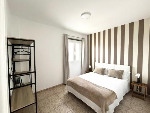 阿雷西费Mahostly Apartamento Comillas SH的卧室配有白色的床和条纹墙