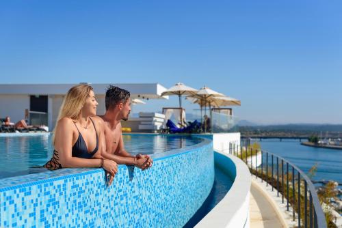 波尔蒂芒Jupiter Marina Hotel - Couples & Spa的坐在游泳池边的男人和女人