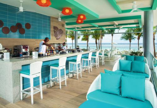 欧丘里欧Riu Ocho Rios - All Inclusive的餐厅设有酒吧,提供蓝色椅子和海洋