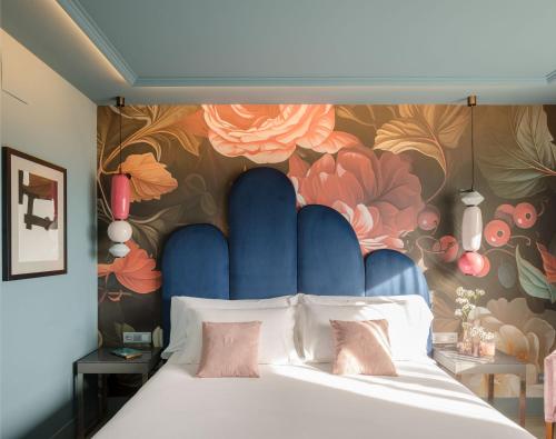 圣塞瓦斯蒂安Hotel Antik San Sebastián的一间卧室设有一张带花卉墙壁的大床