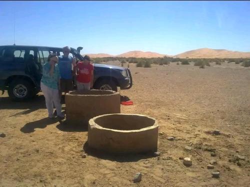 梅尔祖卡GITE Take Ur time的一群人站在沙漠里的一辆卡车旁边