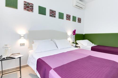 加比切马莱Residence Diffuso Arcobaleno的一间卧室配有两张紫色和绿色的床