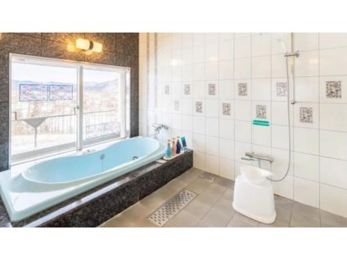 雫石町SHIZUKUISHI RESORT HOTEL - Vacation STAY 29563v的一间带蓝色浴缸和窗户的浴室