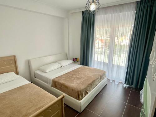 维利波吉Fishta Apartment Q6 37的一间卧室设有两张床,窗户设有绿色窗帘