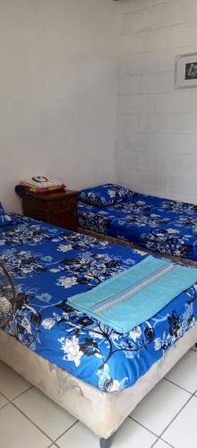 拉利伯塔德Mini casa a dos cuadras de la playa, muy cerca del comercio local的配有蓝色棉被的客房内的两张床