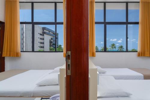 马塞约Ritz Plazamar Hotel的窗户房间里一排床