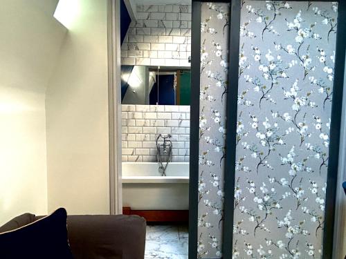 布莱顿霍夫Central Brighton Stylish Studio Apartment的浴室配有浴缸和带鲜花的淋浴帘