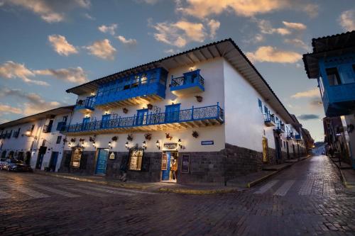 库斯科Hotel Hacienda Cusco Plaza的白色的建筑,在街上有蓝色的窗户