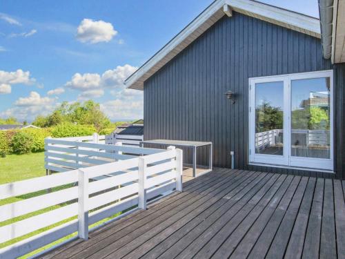 格莱斯堡6 person holiday home in Glesborg的木制甲板上设有白色的围栏和房屋