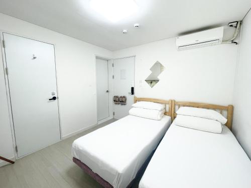 仁川市Koin Guesthouse Incheon airport的白色墙壁客房的两张床