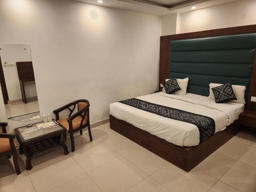 新德里Hotel Marina Near IGI Airport Delhi的一间卧室配有一张床、一把椅子和一张桌子