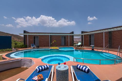 伊加特普里Wabi Sabi Resort, Igatpuri的一座带椅子的游泳池以及一座建筑