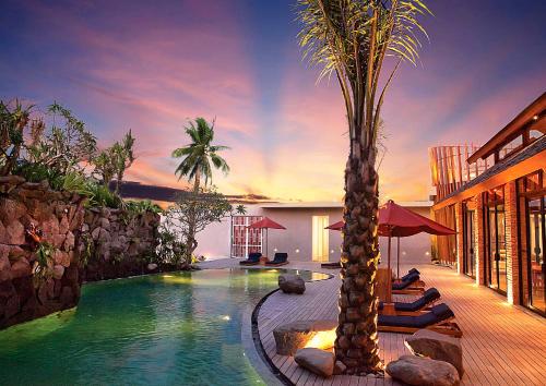 塞米亚克Maca Villas & Spa Bali的一座游泳池,旁边是椅子和棕榈树