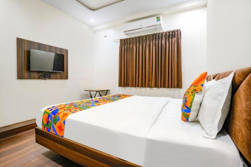 苏拉特FabHotel Raviraj Capital的卧室配有白色的床和电视