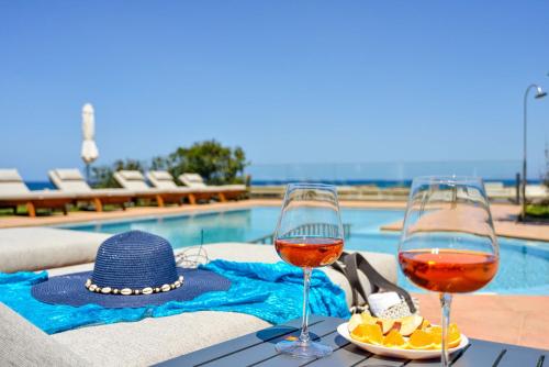 科林瓦里奥Panthea Luxury Living的游泳池畔的桌子上放两杯葡萄酒