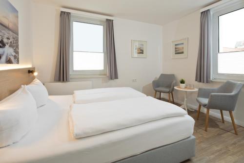诺德奈Haus Menno Janssen - Doppelzimmer的白色卧室配有床和桌椅