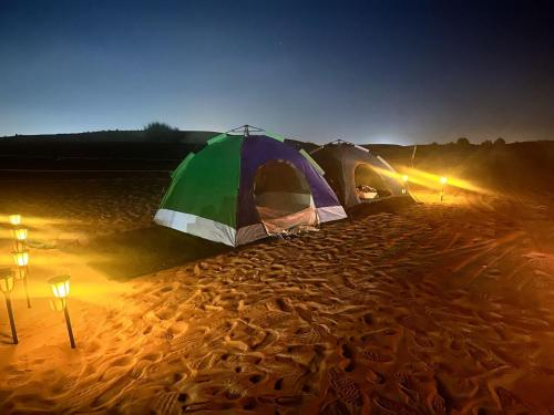 HunaywahRoyal Desert Tourism LLC的夜晚沙漠中的一对帐篷