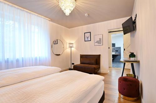 科赫姆泽赫霍夫酒店的一间卧室配有一张床、一把椅子和电视
