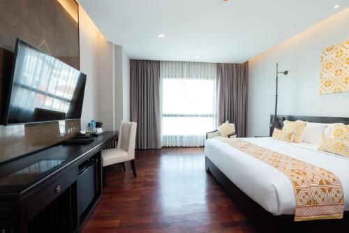 万象Mintra Hotel的酒店客房配有一张床、一张书桌和一台电视。