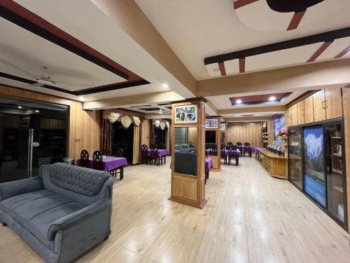 锡卡都Blue Sky Hotel & Restaurant的一间配备有沙发、桌子和紫色椅子的客房