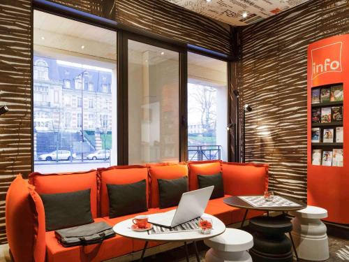 凡尔赛凡尔赛宫宜必思酒店 的一间设有橙色沙发的餐厅,上面装有笔记本电脑