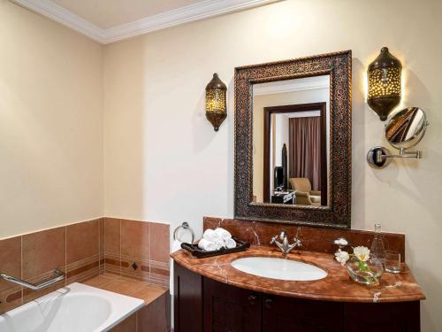 麦纳麦Mercure Grand Hotel Seef - All Suites的一间带水槽和镜子的浴室