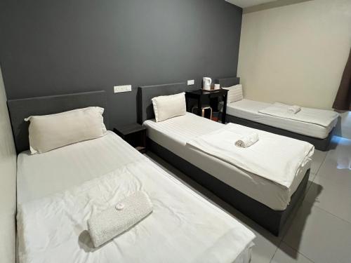 关丹格邦工业园经济型酒店的配有白色床单的客房内的两张床