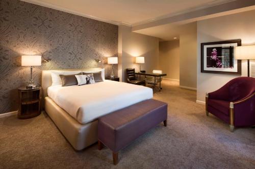 圣何塞Hotel De Anza, a Destination by Hyatt Hotel的配有一张床和一把椅子的酒店客房
