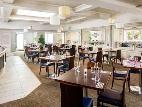 西布罗姆维奇Mercure Birmingham West Hotel的用餐室设有桌椅和窗户。