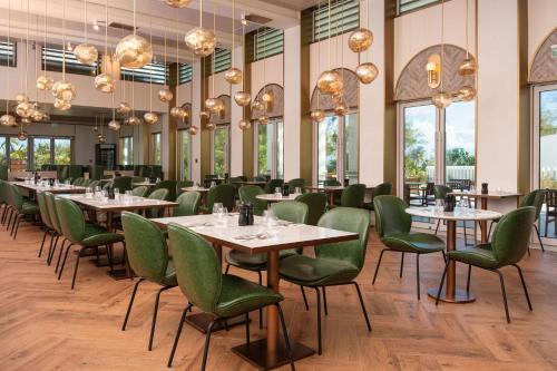 圣菲利普Wyndham Grand Barbados Sam Lords Castle All Inclusive Resort的用餐室设有桌子和绿色椅子以及窗户。