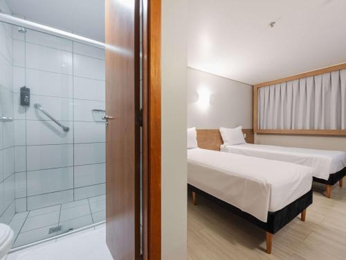 戈亚尼亚ibis Styles Goiânia Shopping Estação的客房设有两张床和玻璃淋浴间。