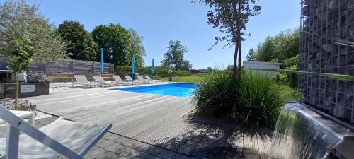 赫拉尔兹贝亨Vakantievilla - B&B Blue Garden Vlaamse Ardennen的一座带躺椅的游泳池位于大楼旁