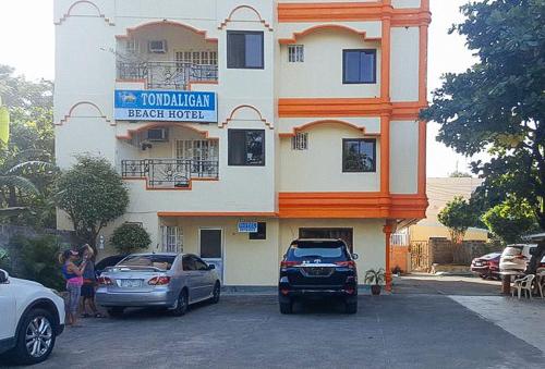 达古潘RedDoorz @ Tondaligan Beach Hotel的两辆车停在大楼前的建筑物