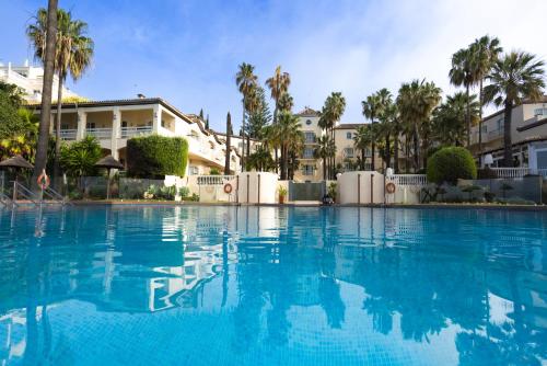 EsteponaLas Dunas Grand Luxury的一座棕榈树和建筑的大型游泳池
