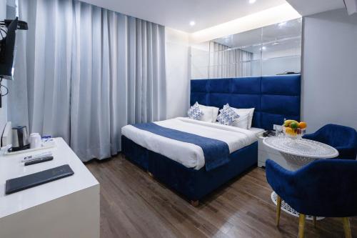 钱德加尔Hotel Downtown 17的一间酒店客房,配有一张蓝色的床和一张书桌