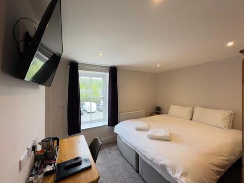 马汉莱斯白狮酒店的一间卧室配有一张床、一张书桌和一台电视