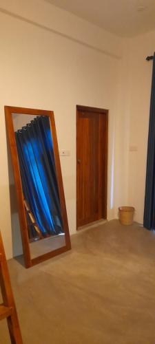 阿鲁甘湾Surf Gangs Arugambay的一间设有镜子的客房和一扇带蓝色窗帘的门