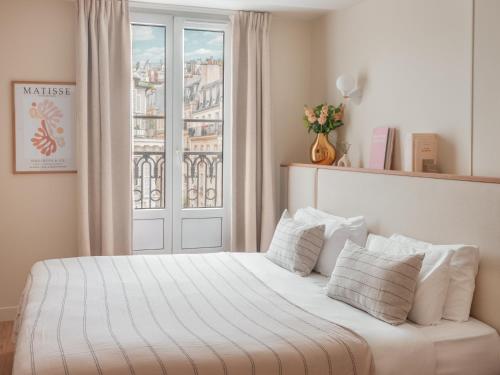 巴黎巴斯酒店的一张带白色床单和枕头的床,位于窗户前